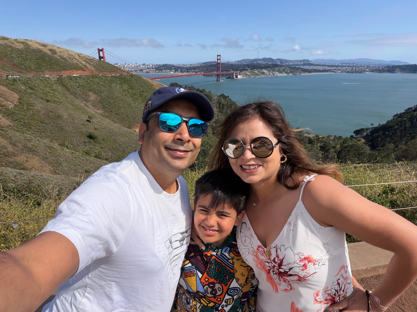 Our family smiling above the blue bay with the Golden Gate Bridge behind us.