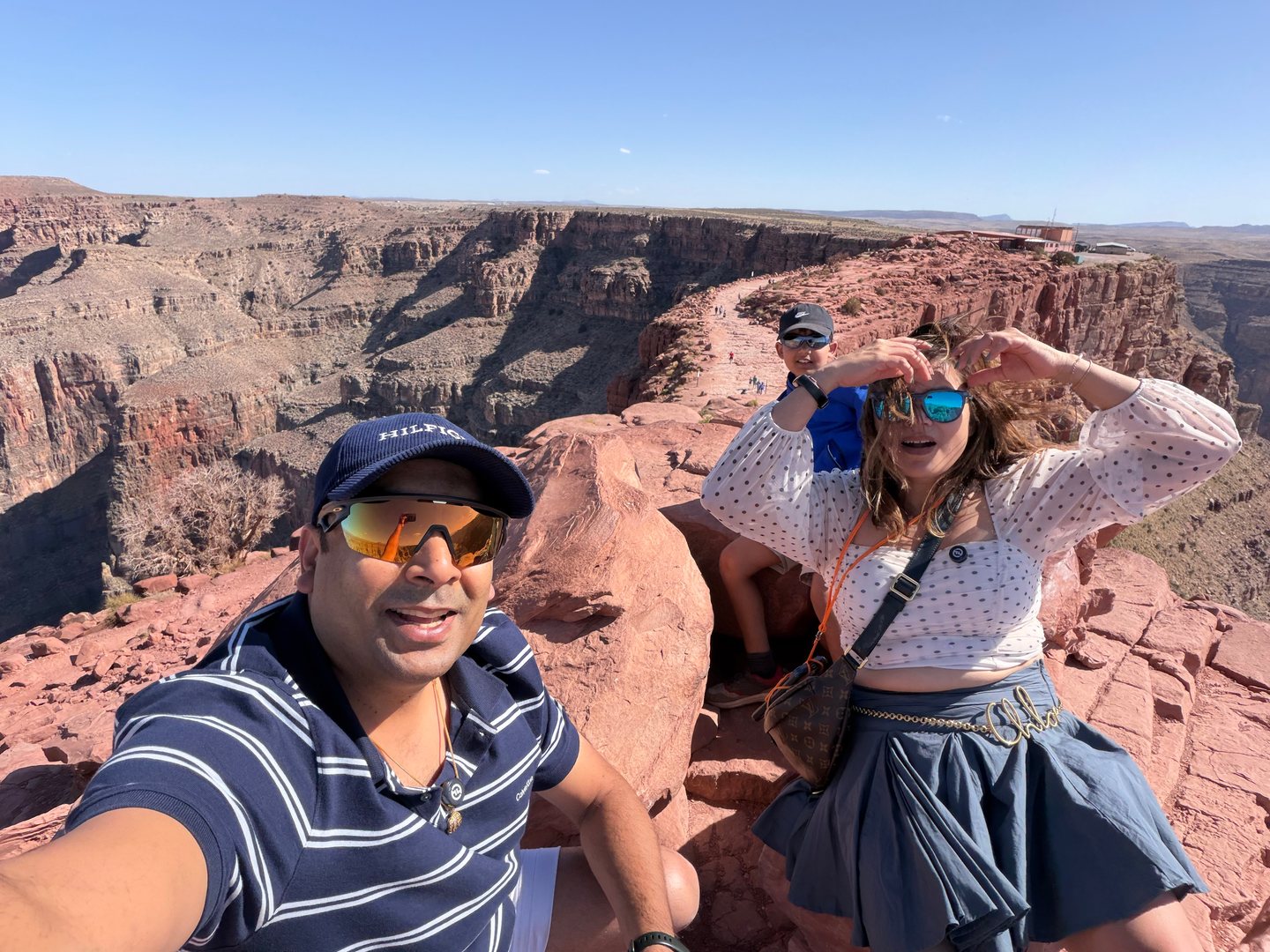 Our family taking a selfie on red rock above an expansive canyon.