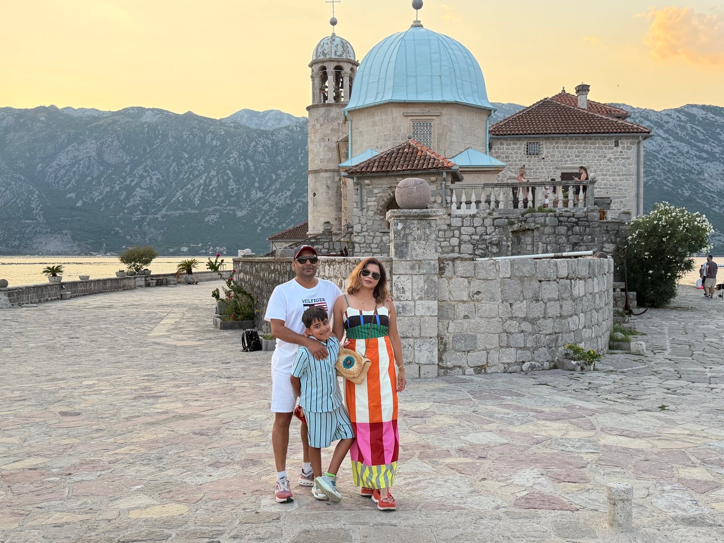 Our family beside a domed stone church, with mountains and water in the evening light.