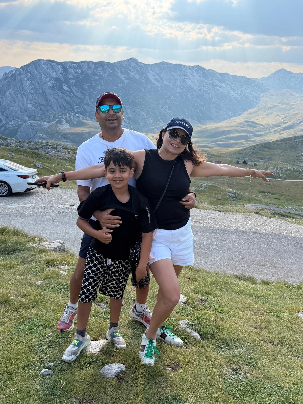 Our family standing beside a mountain road with a dramatic rocky ridgeline and sunlight behind us.